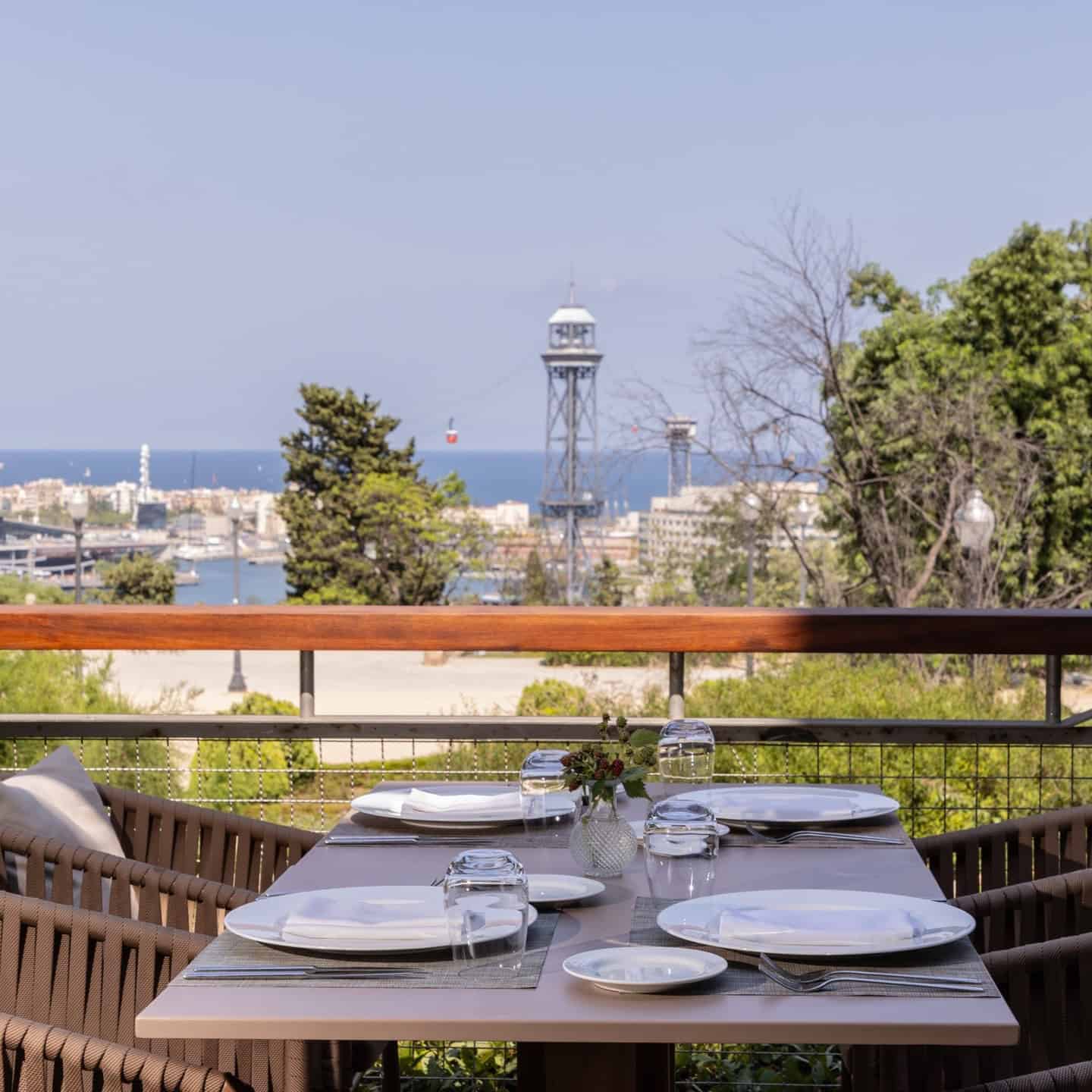 Outdoor dining table set for four with stunning city and sea views—experience Barcelona dining at its finest on a sunny day.