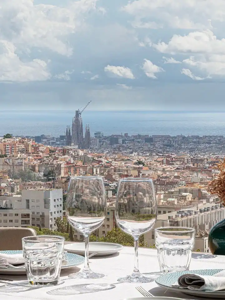 Table set for dining overlooking a cityscape with the sea and clouds in the background, perfect for exploring Restaurants with a View featured in the Barcelona Guide.