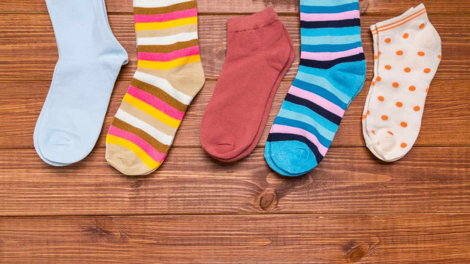 Five colorful socks, each with different patterns, laid out side by side on a wooden surface.