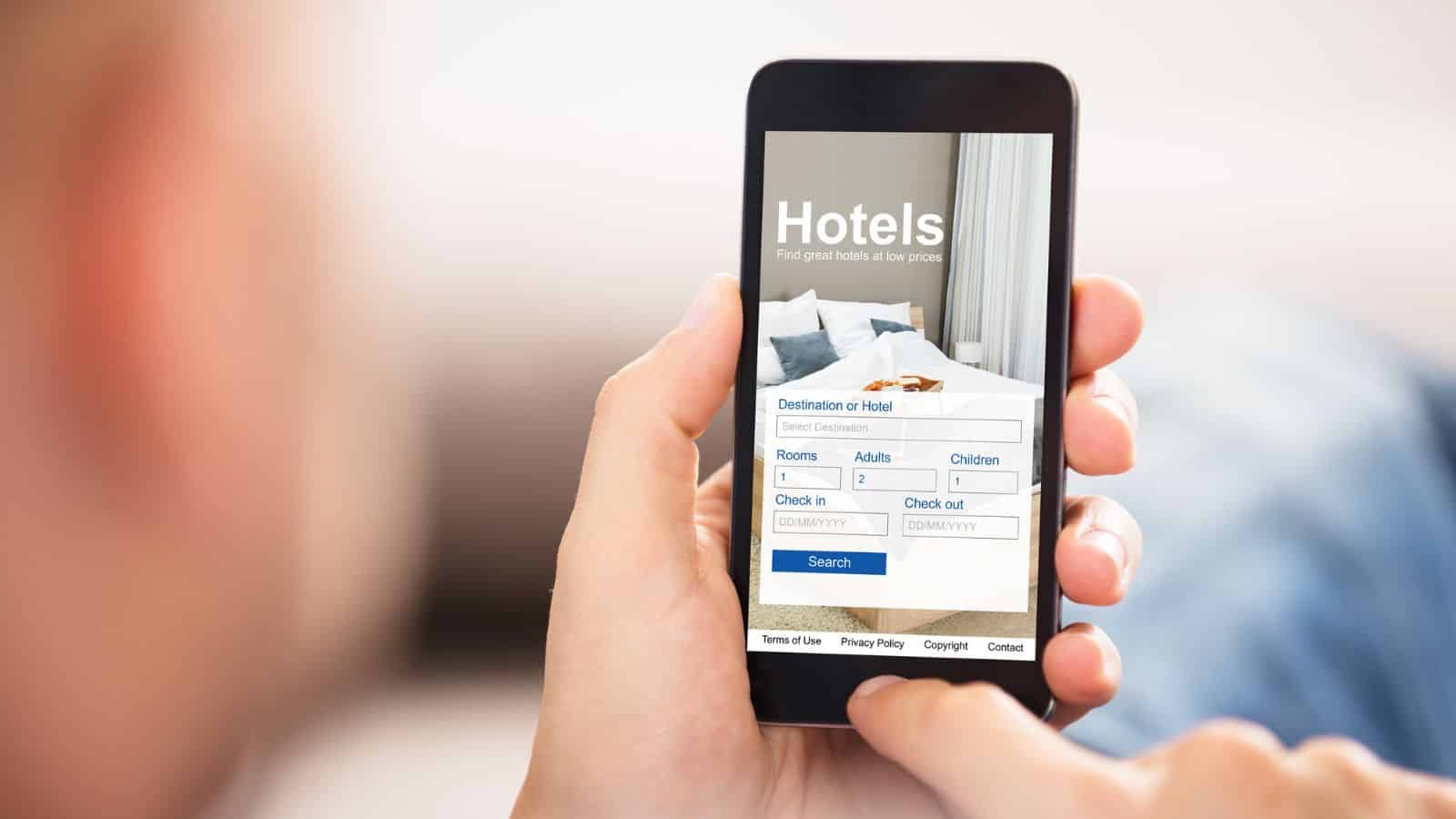 Person holding a smartphone with a hotel booking website open on the screen.