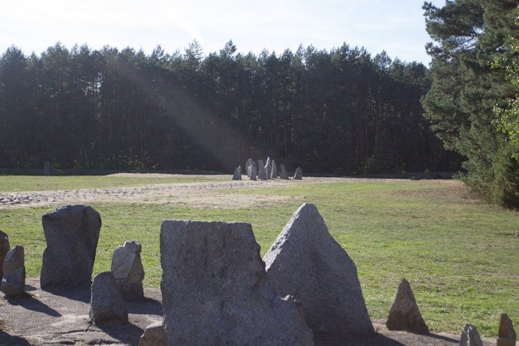 Large stone slabs arranged in a grassy field, with a forest in the background under a clear sky—scenes like this await those visiting Poland’s picturesque countryside.