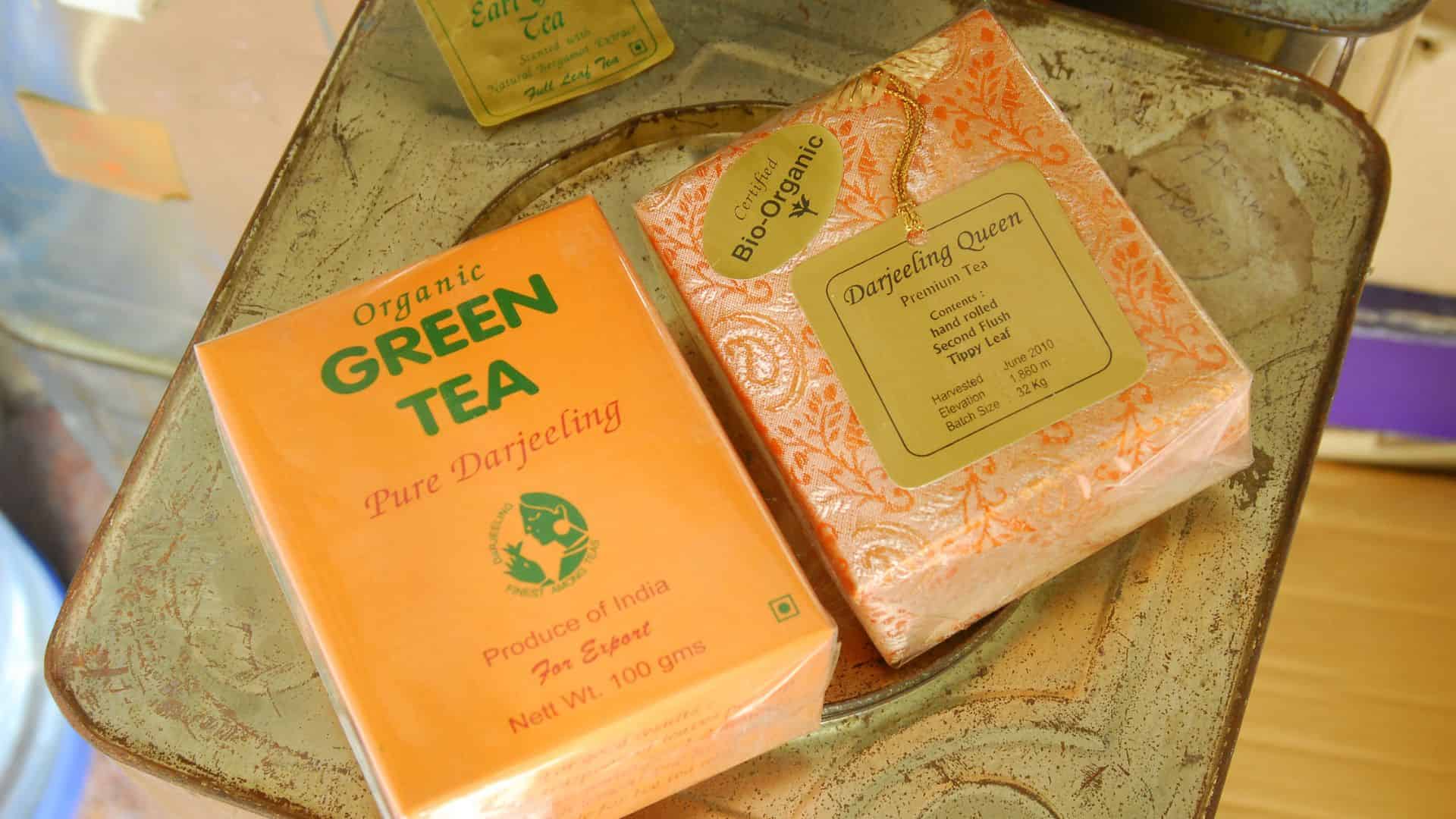 Two boxes of Darjeeling green tea with orange packaging placed on a metallic surface.
