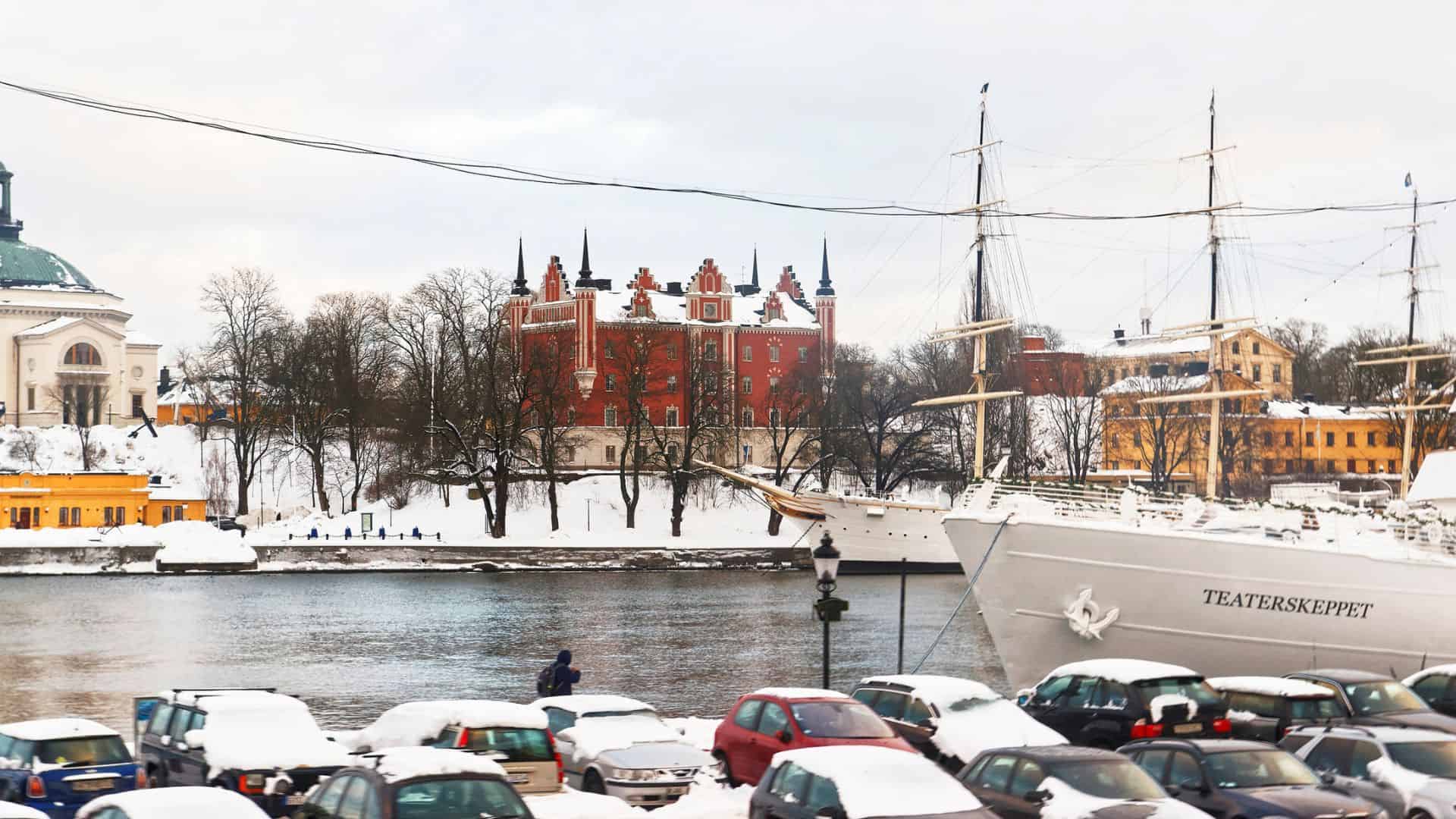 Snow-covered cityscape with historic buildings and a docked ship in Stockholm, Sweden.