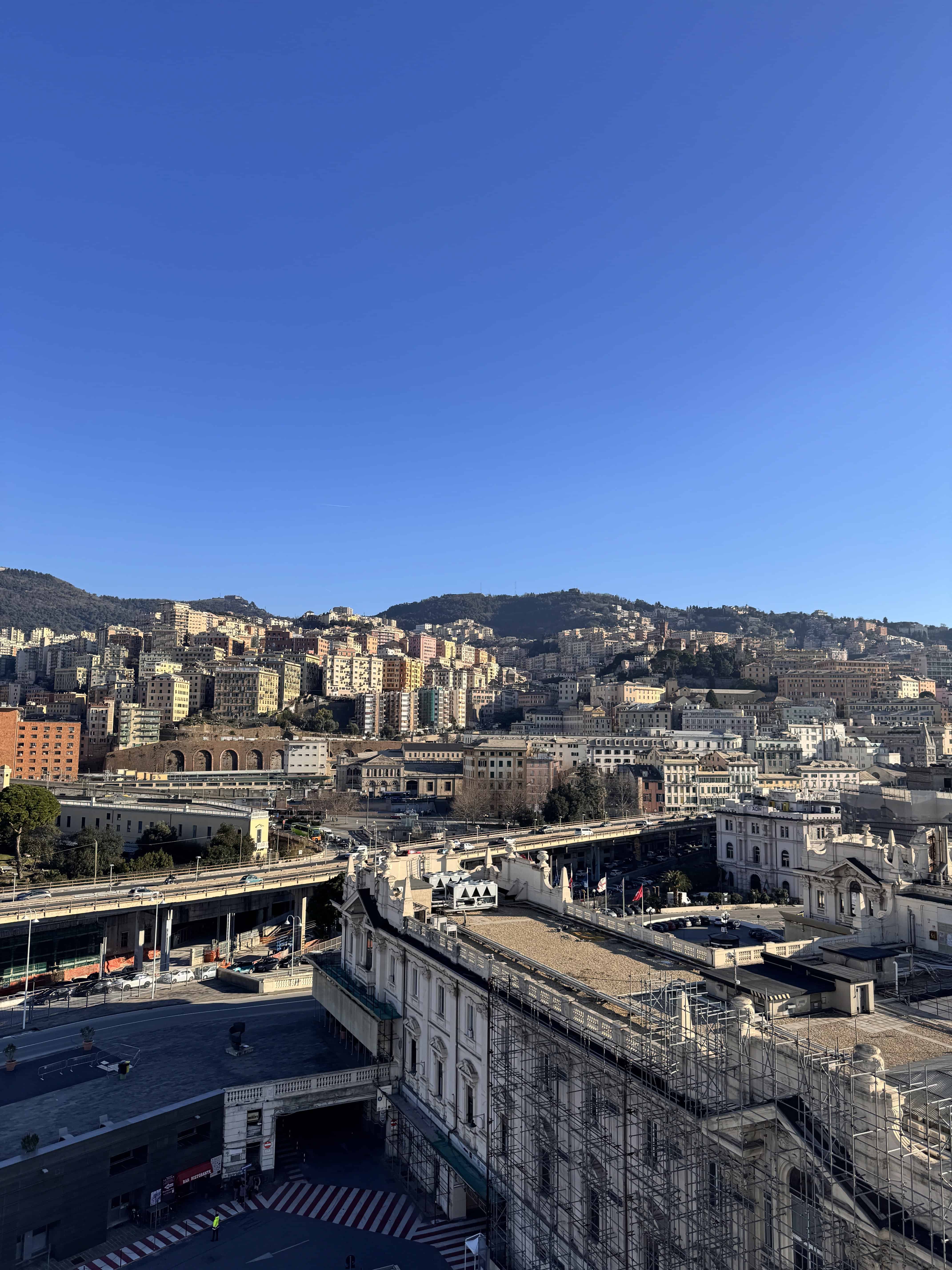 Cityscape of Genoa, Italy, with many buildings on a hillside under a clear blue sky, seen from an elevated viewpoint—perfect for experiencing 24 hours in Genoa.