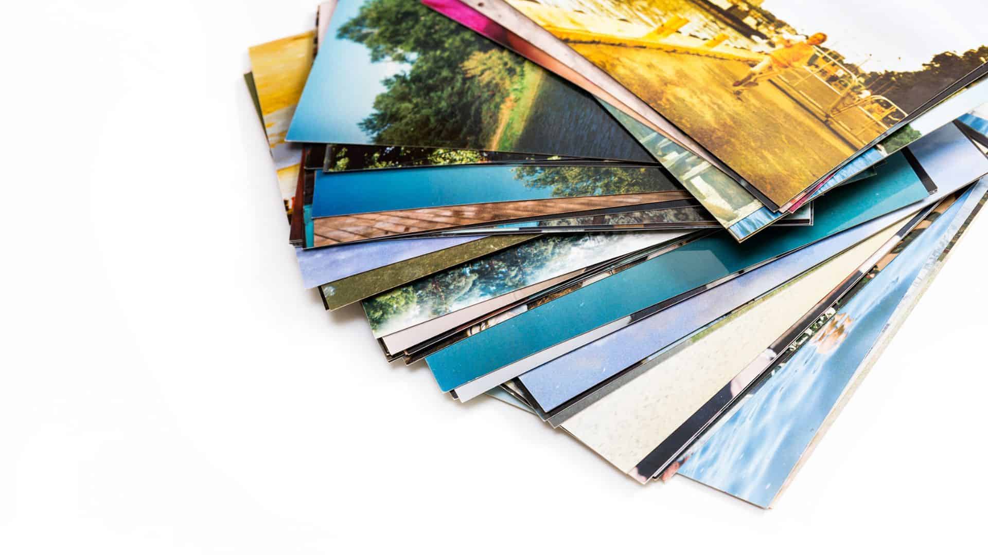 A stack of colorful printed photographs scattered on a white surface.
