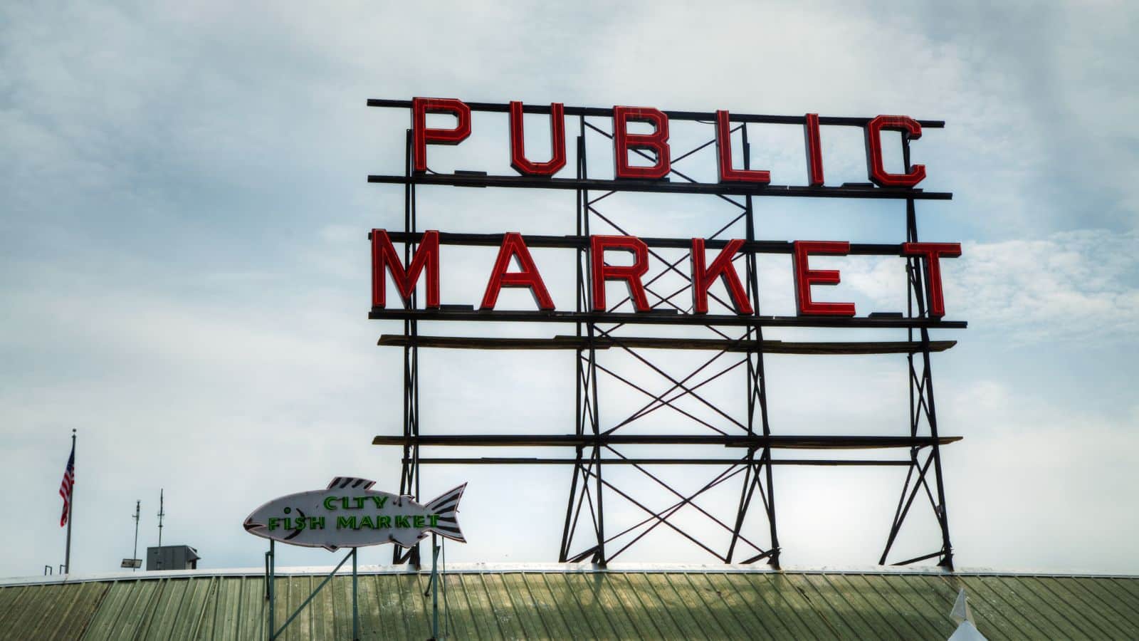 Large red "PUBLIC MARKET" sign on metal beams above a rooftop, with a fish-shaped "CITY FISH MARKET" sign below.
