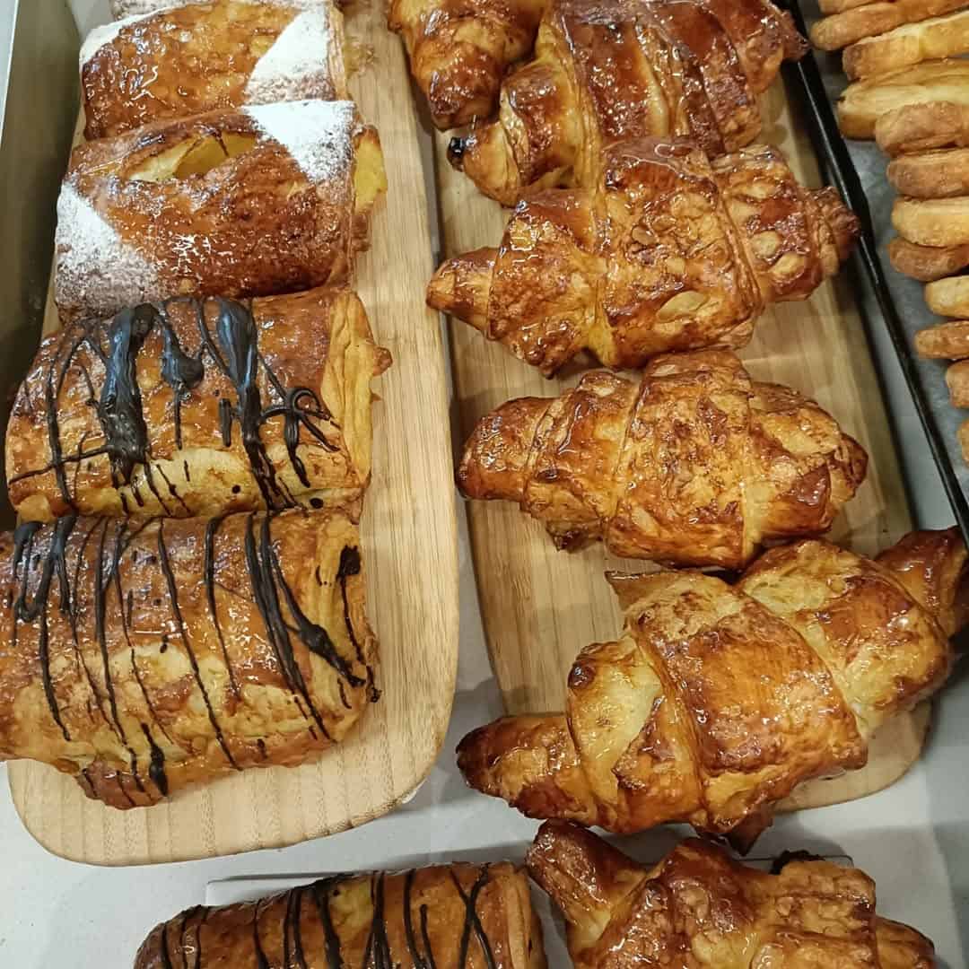Assorted pastries, including croissants and chocolate-drizzled puff pastries, displayed on wooden boards—perfect for those exploring gluten free Barcelona delights.