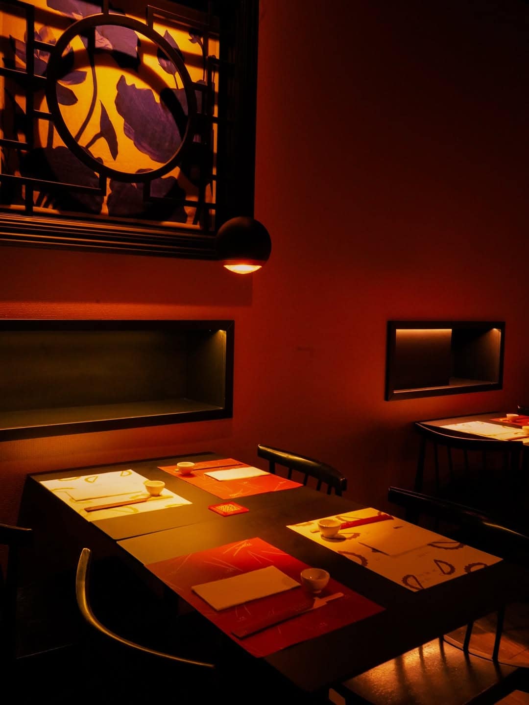 Dimly lit restaurant with set tables and warm orange lighting, featuring decorative wall art above—an inviting spot for a Gluten Free Barcelona dining experience.