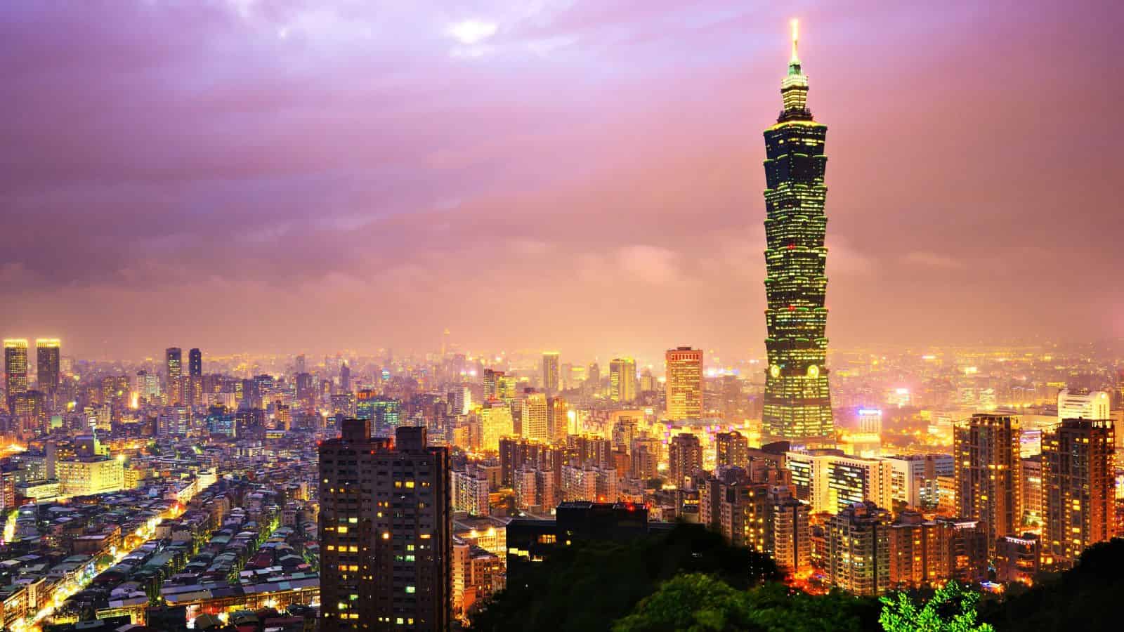 Taipei city skyline at dusk with Taipei 101 tower illuminated against a colorful sky.