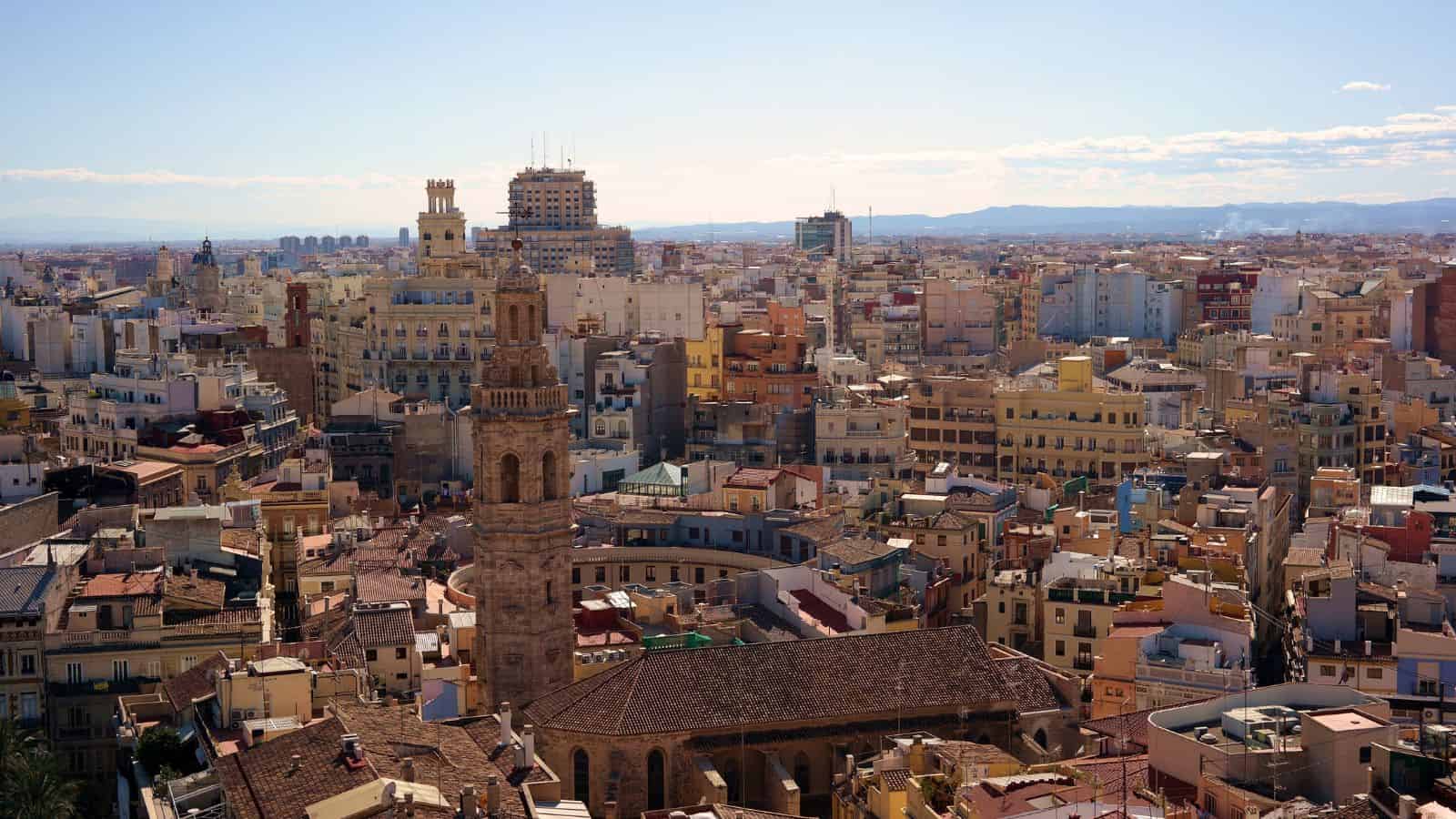 Cityscape of Valencia, Spain, featuring historic buildings and a central bell tower under a clear sky.