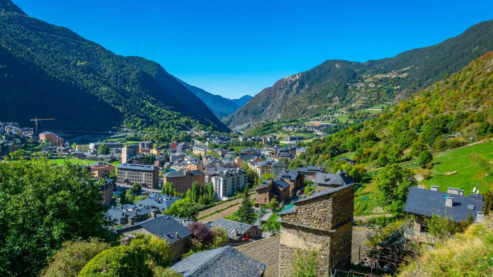 A scenic mountain town nestled in a green valley under a clear blue sky.