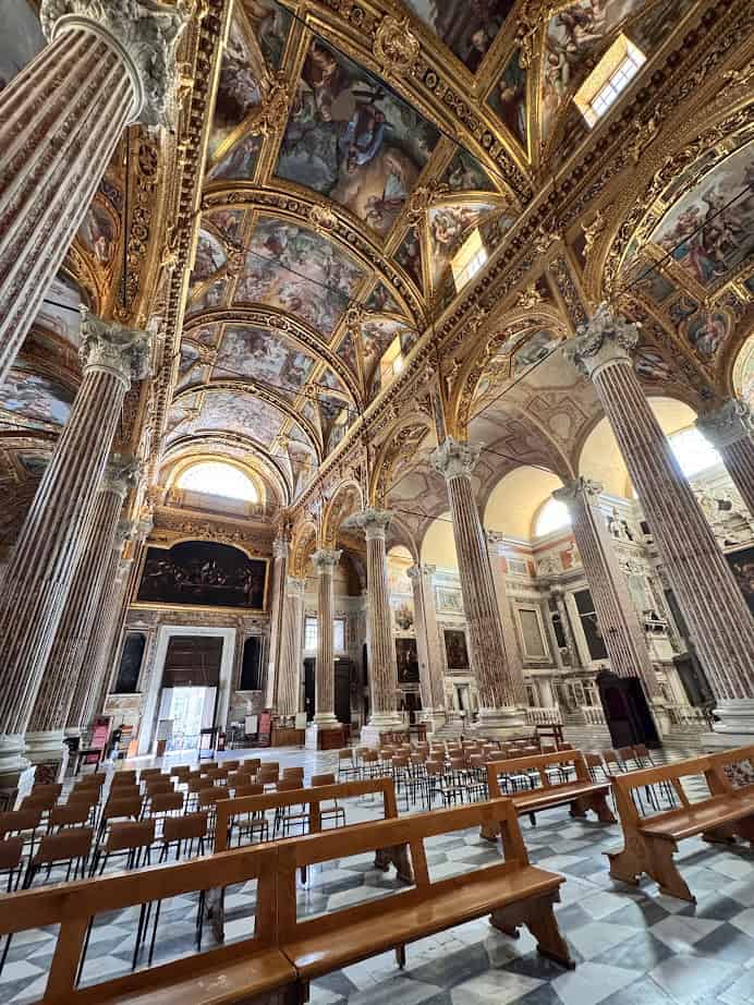 Ornate church interior in Genoa, Italy, featuring marble pillars, arched ceiling, frescoes, and empty wooden pews—perfect to explore in 24 hours.