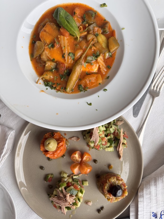 Two plates: one with vegetable stew in red sauce, the other with assorted appetizers and salad on a beige plate—perfect flavors to experience during your Tunisia itinerary 1 day adventure.