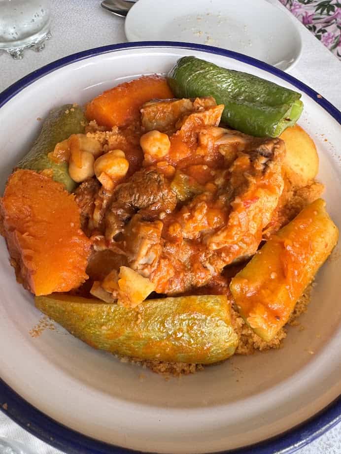 A bowl of couscous topped with vegetables, chickpeas, and meat in a tomato-based sauce—an essential dish to try on your Tunisia itinerary 1 day adventure.