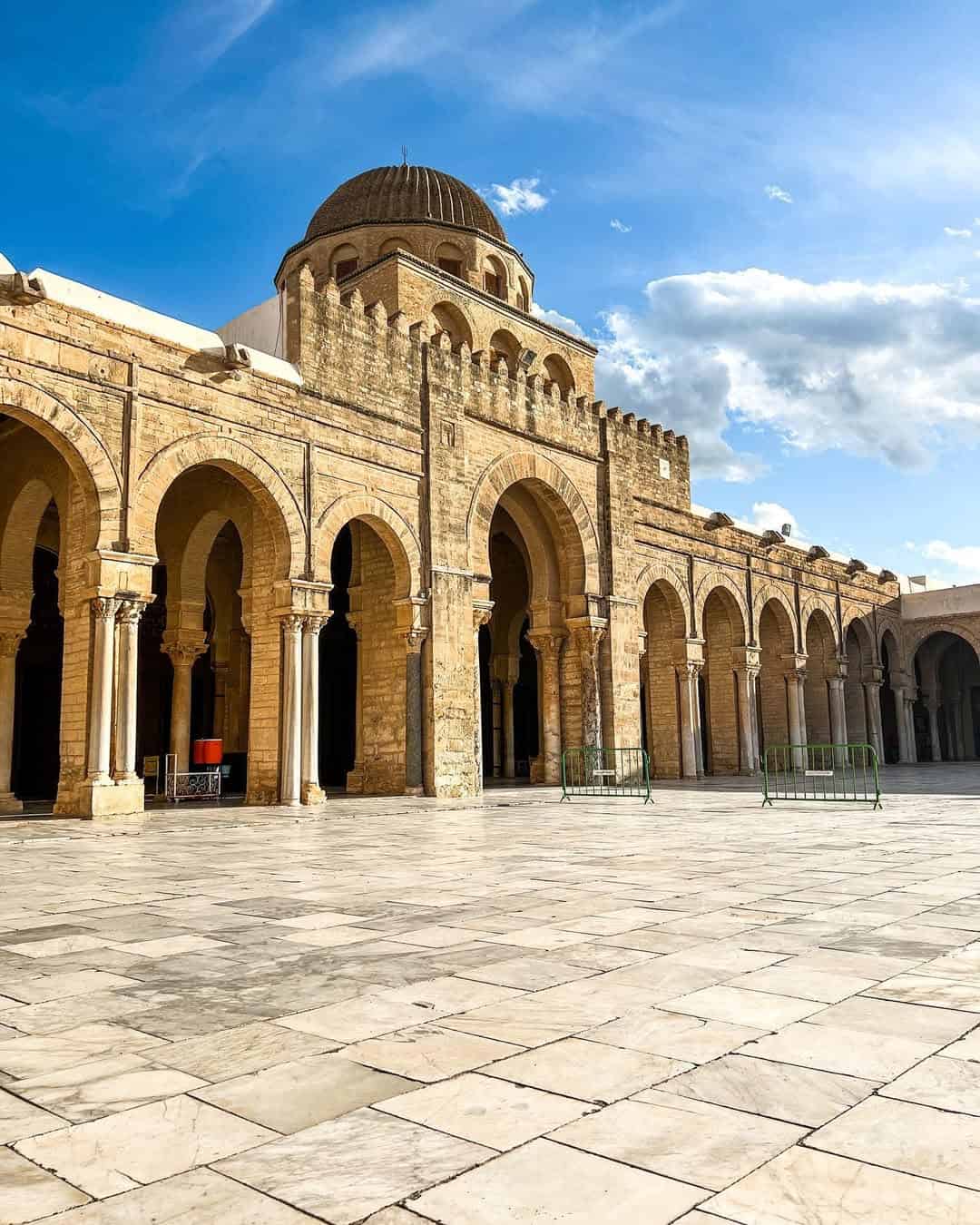 Ancient stone arches and the domed roof of the Great Mosque of Kairouan under a blue sky—a must-see on any Tunisia itinerary 1 day adventure.