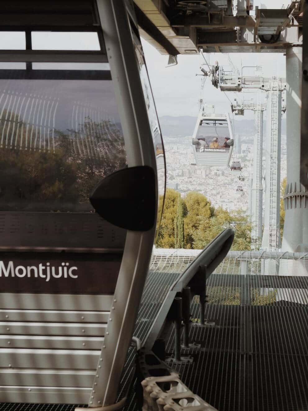 Cable cars at Montju&iuml;c, Barcelona, glide above the cityscape and lush trees&mdash;an essential spot to include in your Barcelona itinerary for those spending 4 days in Barcelona or planning their next Barcelona travel adventure.