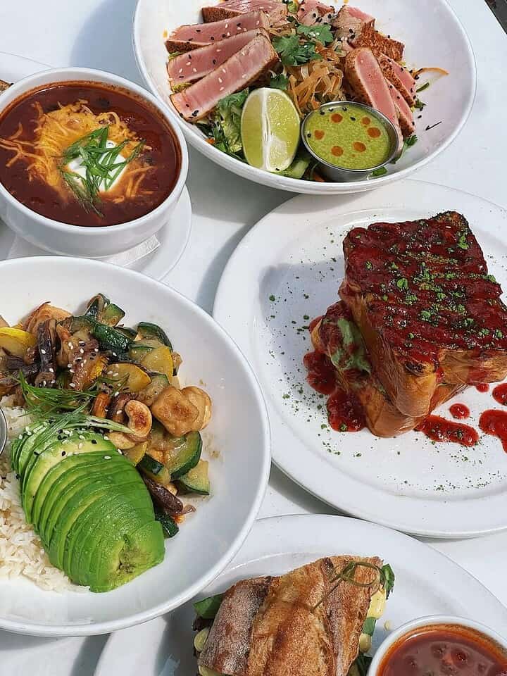 Four plates of colorful, fresh food&mdash;seared tuna salad, soup, avocado rice bowl, and a sandwich&mdash;bring cruise ship food to mind, delivering a dining at sea experience right at your table.