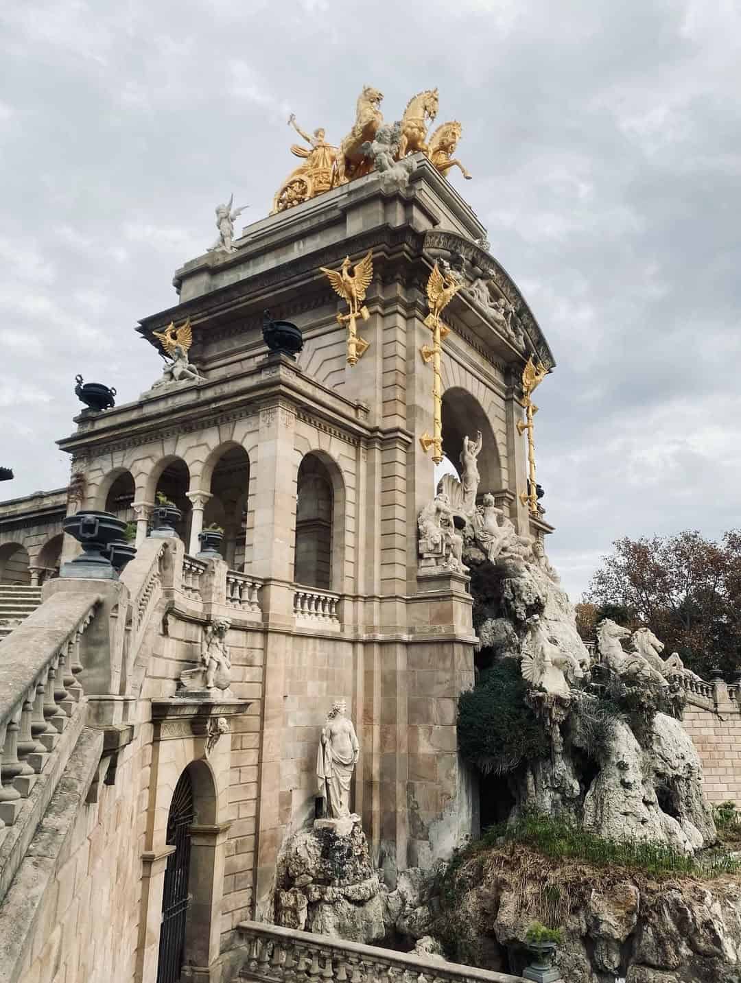 Ornate stone monument with golden statues and sculptures under a cloudy sky&mdash;a must-see on your Barcelona travel adventure or while planning 4 days in Barcelona.