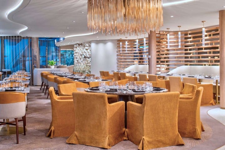 Modern restaurant with gold upholstered chairs, set tables, ambient lighting, and contemporary decor&mdash;perfect for dining at sea and enjoying an upscale experience reminiscent of cruise ship food.