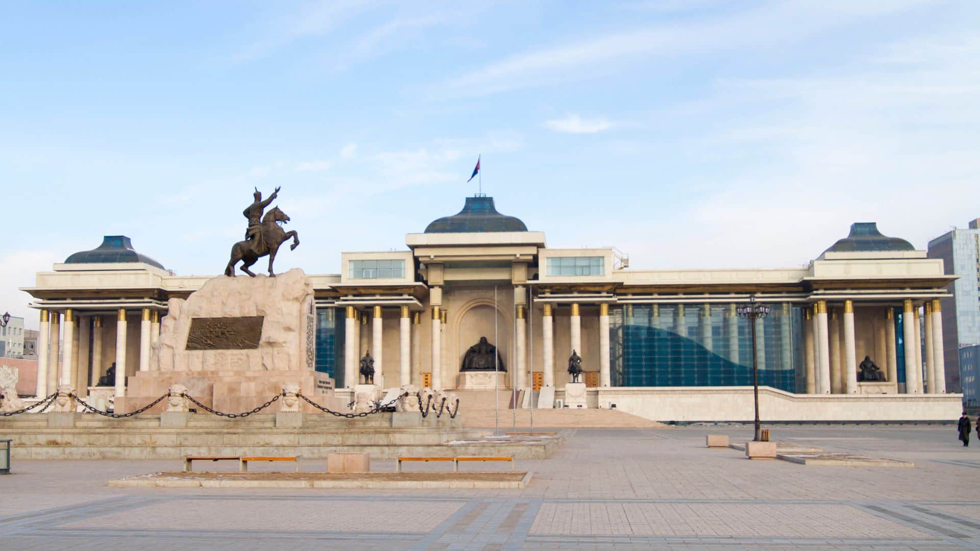 Large government building with columns, statues, and a rider on horseback in a central city square.