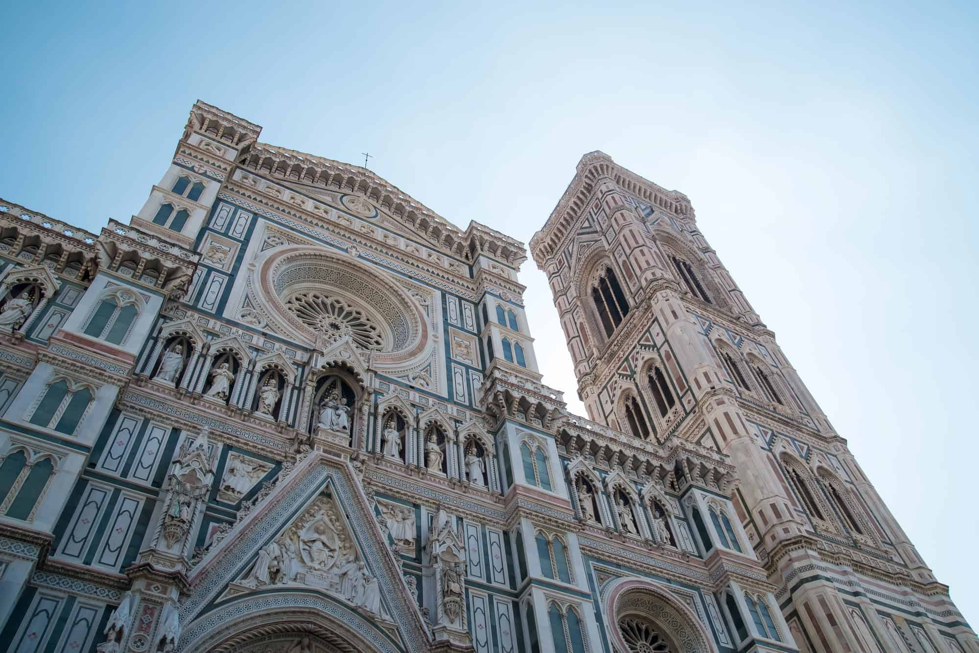 Facade and bell tower of Florence’s Cathedral in Tuscany, featuring ornate marble and detailed architectural carvings.
