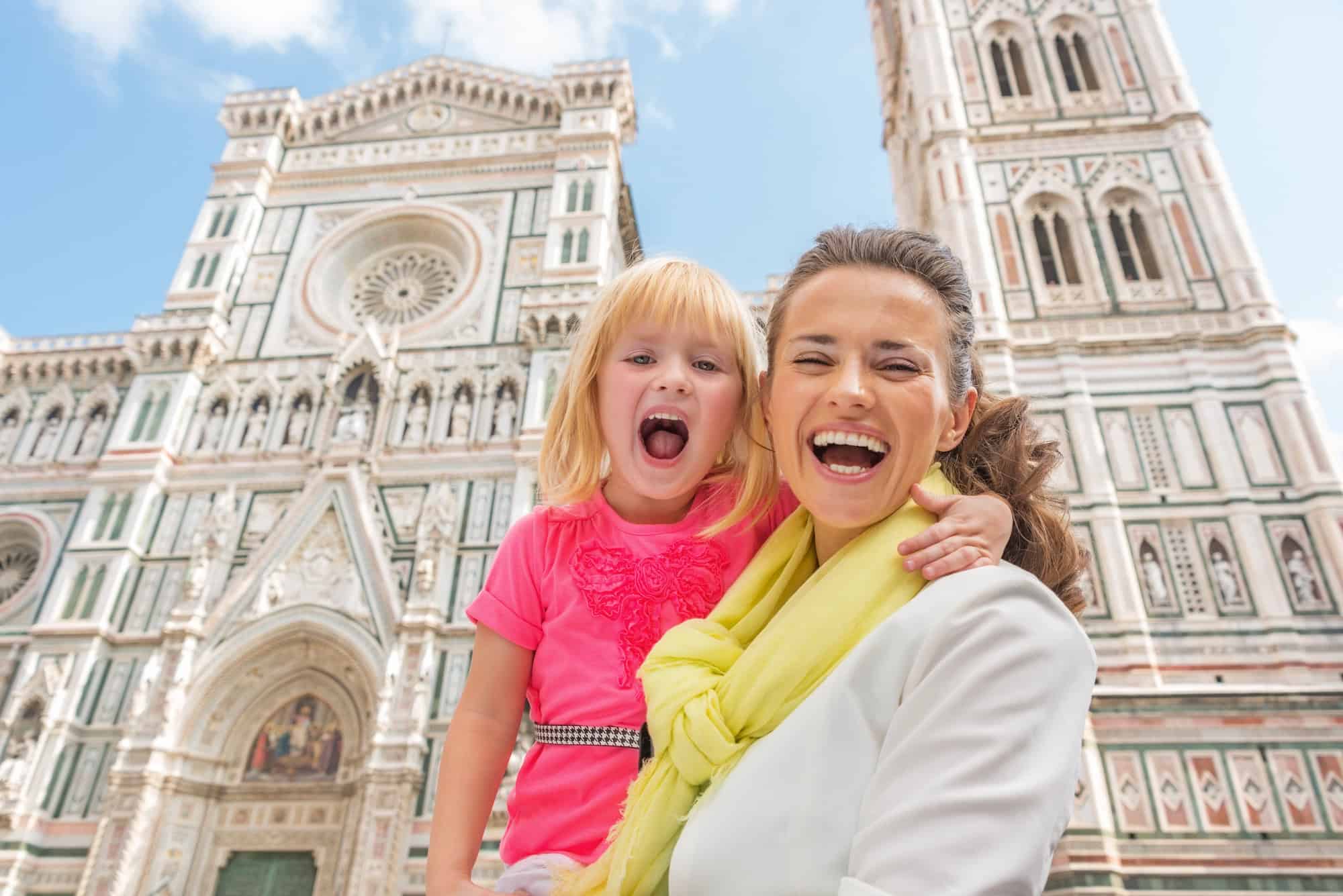 Smiling woman and young girl pose in front of the Florence Cathedral in Italy on a sunny day, capturing a perfect memory for their Florence Italy itinerary.