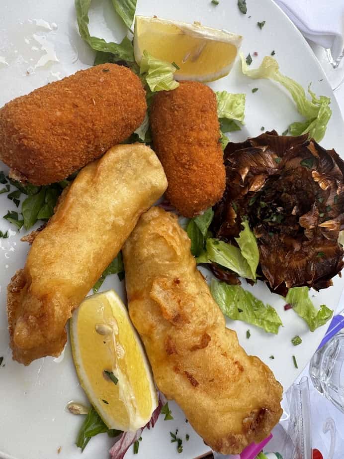 Fried fish, croquettes, grilled artichoke, lettuce, and lemon wedges on a white plate—perfect for adding local flavor to your Family Itinerary while exploring Rome with Kids.
