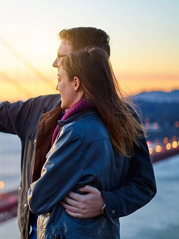 A couple takes a selfie together at sunset near the Golden Gate Bridge in San Francisco.
