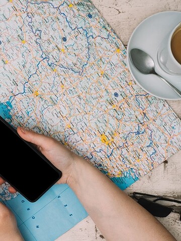 Two people planning a trip with a map, smartphone, coffee cups, sunglasses, and a passport on a table.