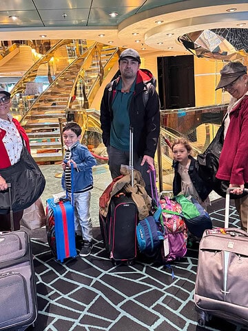 A group of people with luggage in a lobby, showcasing the excitement of multi generational travel.