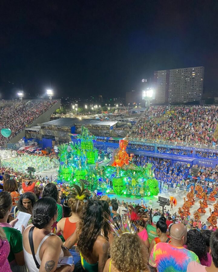 A colorful parade with dancers and floats fills a crowded stadium at night, likely during a carnival celebration&mdash;an unforgettable experience for world travel enthusiasts seeking the best festivals.