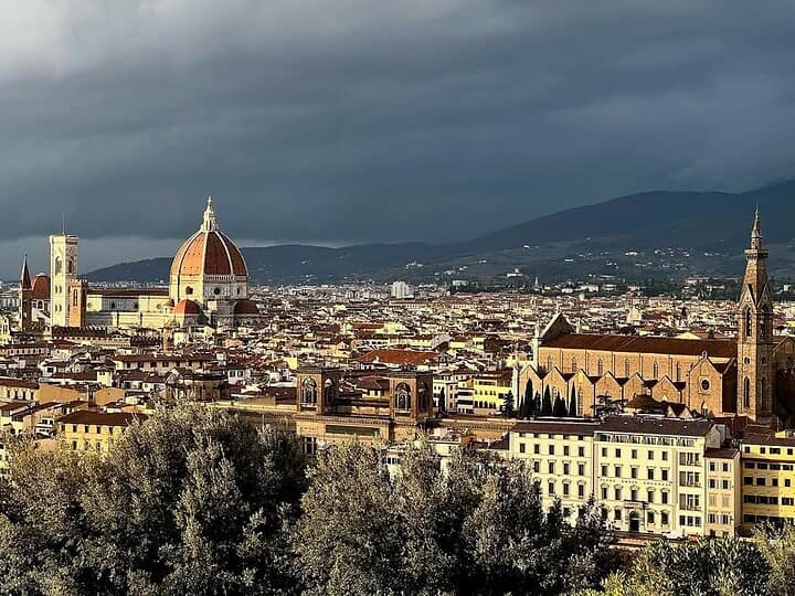 Florence cityscape with the Duomo and historic buildings under a dramatic, cloudy sky&mdash;a must-see on any Florence Italy itinerary.