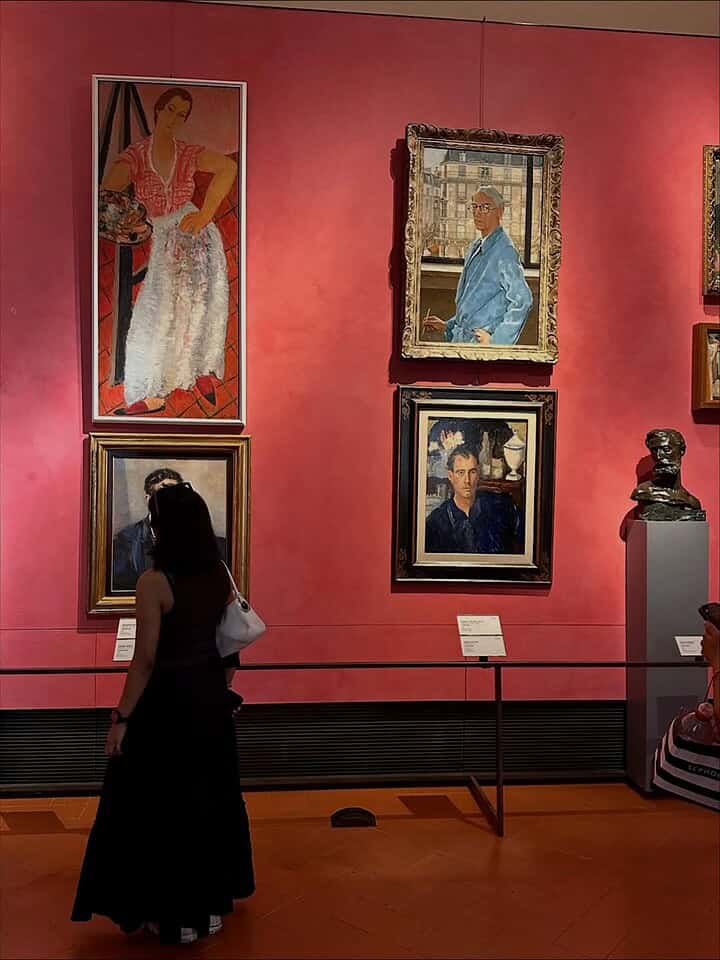 A woman observes paintings and a bust in an art gallery with red walls, a perfect stop on any Florence Italy itinerary.