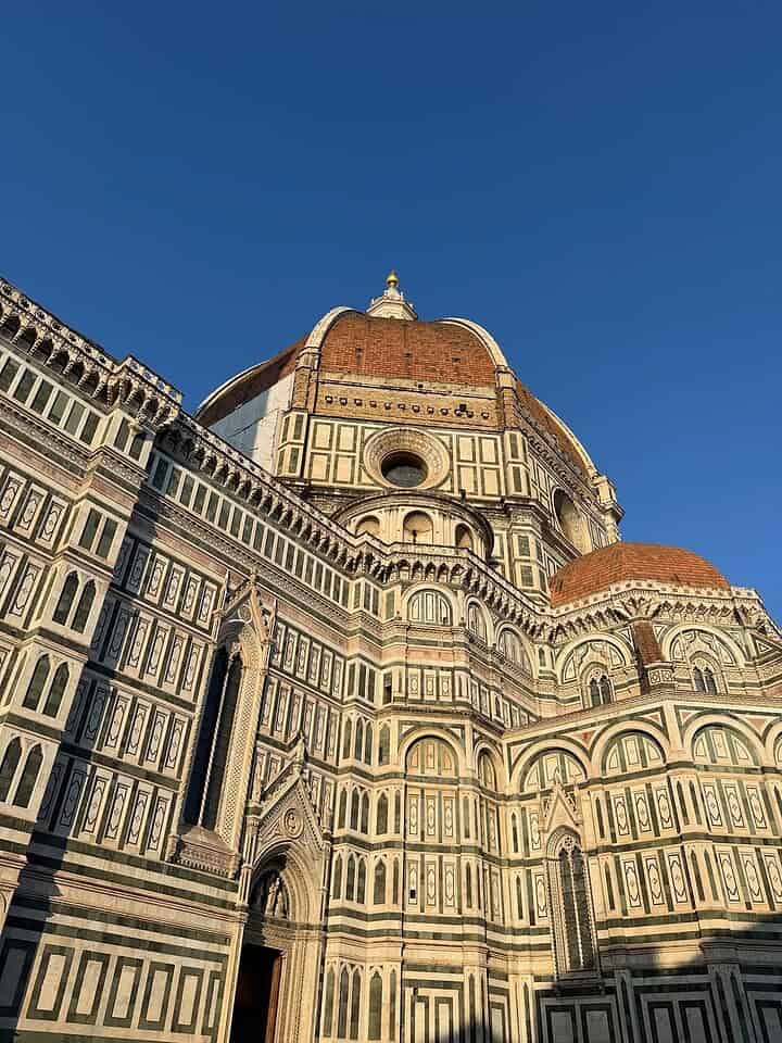 The Florence Cathedral with its iconic dome, captured under a clear blue sky in warm sunlight&mdash;a must-see highlight on any Florence Italy itinerary.