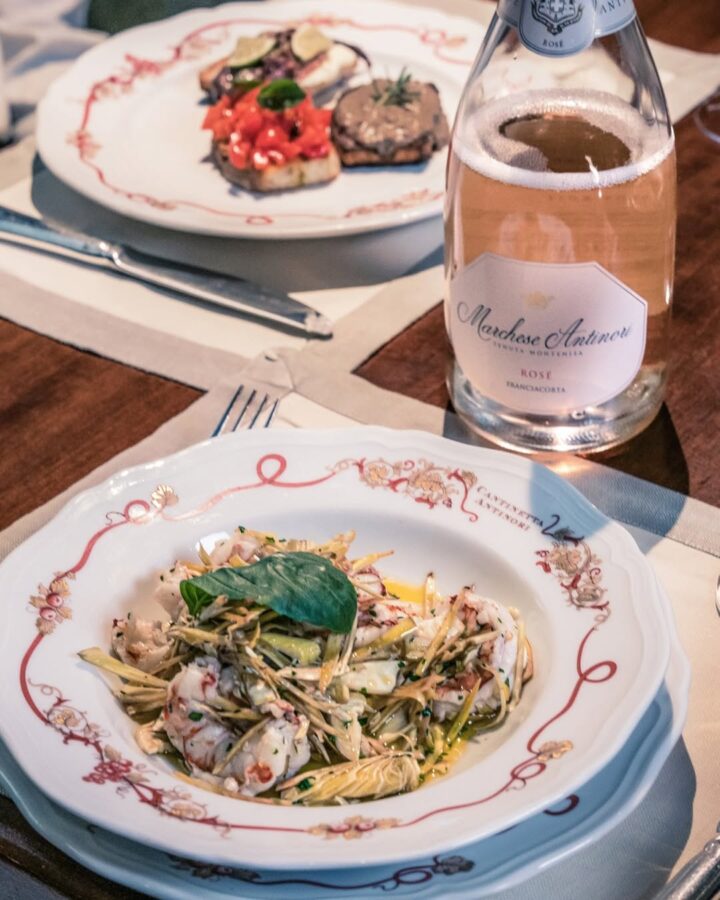 A plate of seafood salad, bruschetta, and a bottle of ros&eacute; wine set on a dining table captures the essence of Florence food at its finest.