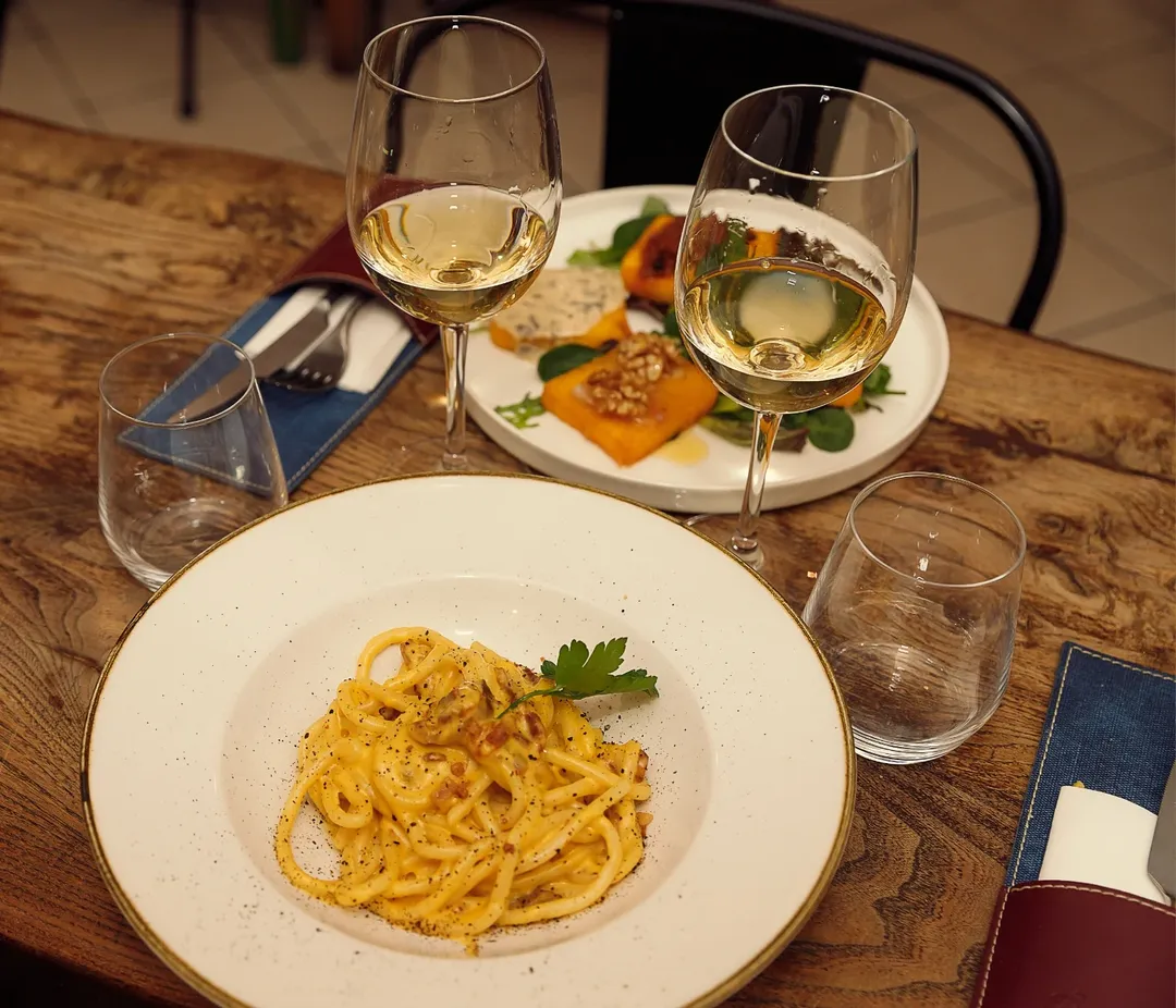 A plate of pasta and wine glasses on a table capture the essence of Florence food, inviting you to savor authentic Italian flavors.