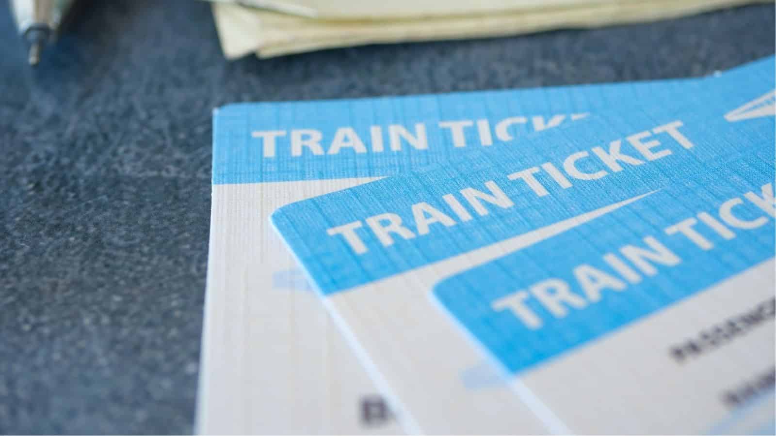 Close-up of two blue and white train tickets placed on a gray textured surface.