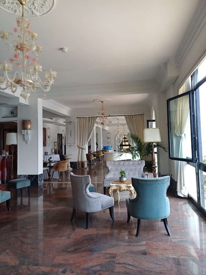 Elegant hotel lounge with plush chairs, marble floors, chandeliers, and large windows letting in natural light—an ideal retreat after spending 4 days in Castel Gandolfo.
