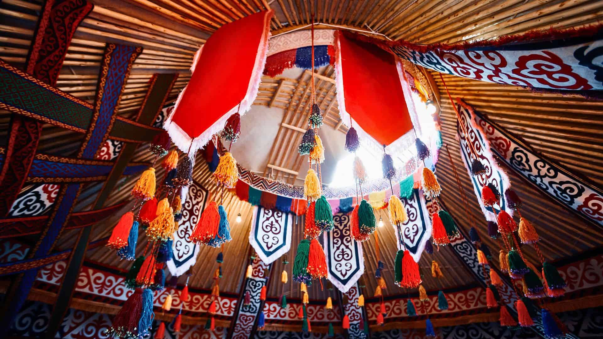 Colorful tassels and patterned fabric decorate the circular roof opening of a traditional yurt.