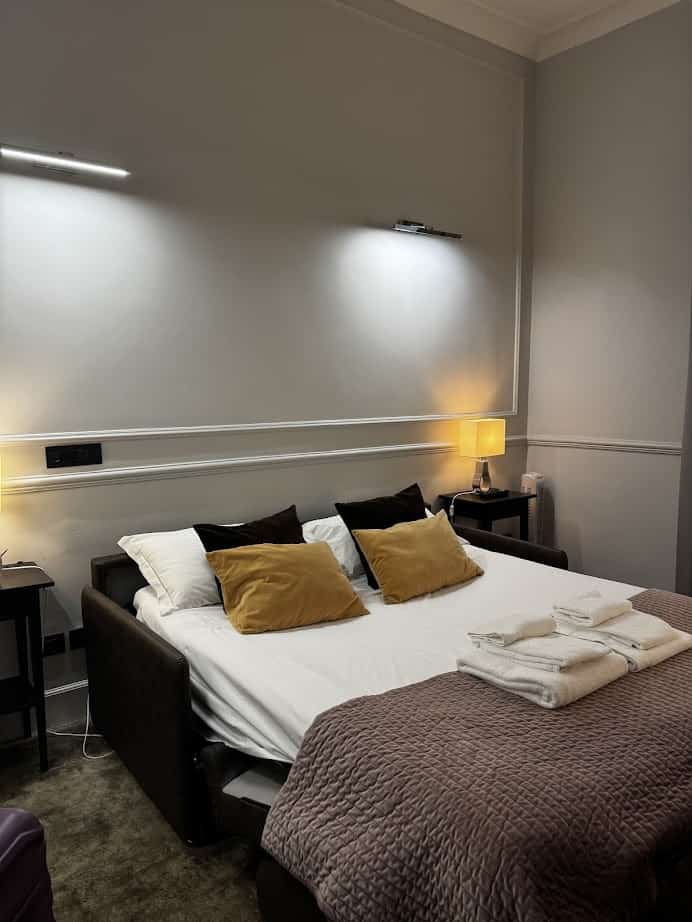 A neatly made bed with pillows, folded towels, and warm lighting creates a cozy, modern bedroom—perfect for families planning their next adventure with a Vacation Trip Planner or exploring Rome with Kids.