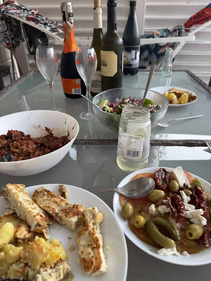 A table set at Parco della Gallinara with wine, salad, empty glasses, and plates of Mediterranean-style food and casseroles.