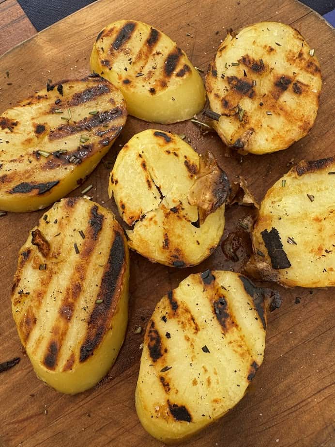 Grilled potato slices with char marks and herbs on a wooden board, perfect for enjoying after 4 days in Castel Gandolfo.