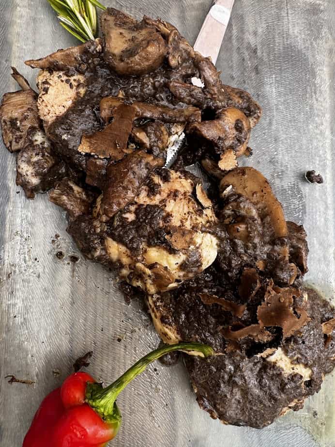 A cooked steak covered in a dark mushroom sauce, garnished with herbs and a red chili pepper—perfect after 4 days in Castel Gandolfo.