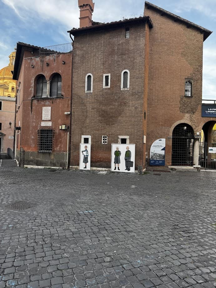Two historic brick buildings with small windows and painted figures on doors in a cobblestone square, perfect for adding to your Family Itinerary when exploring Rome with Kids.