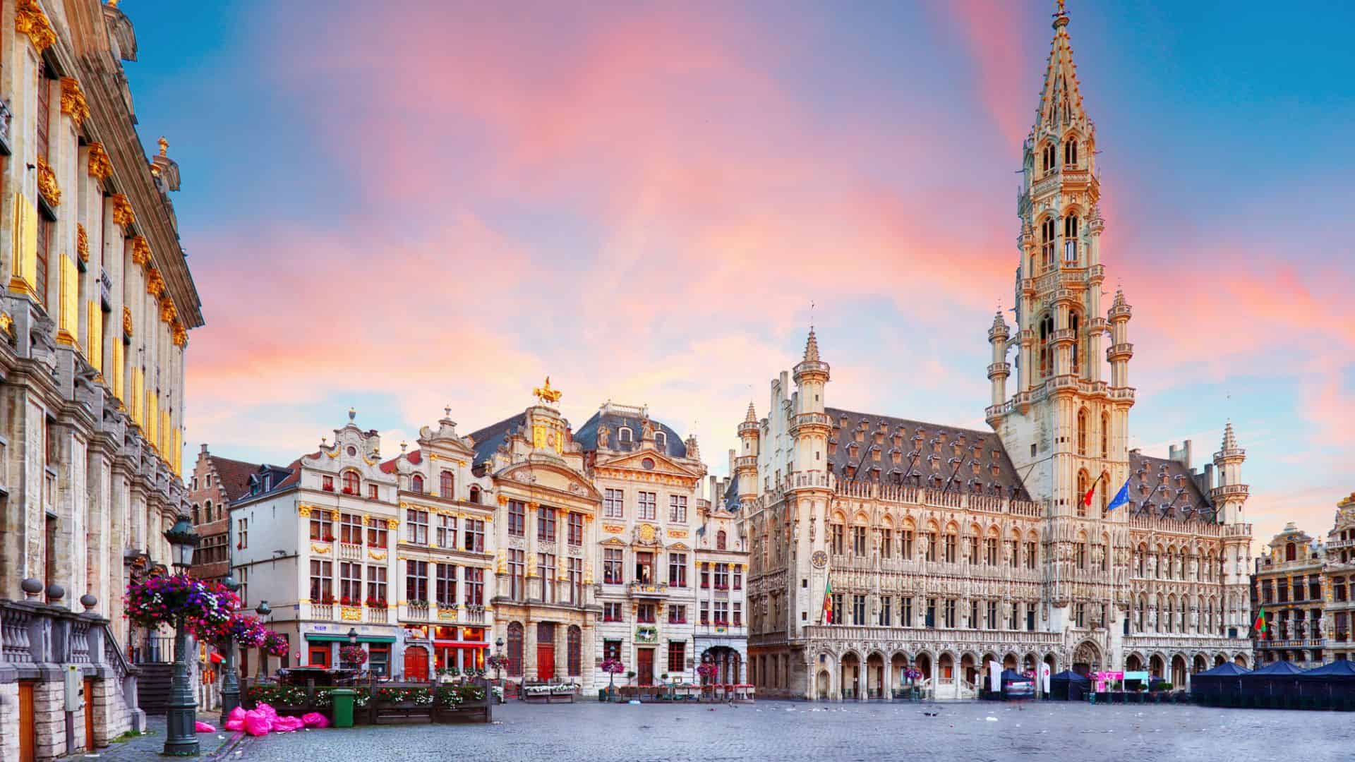Grand Place in Brussels at sunset, featuring historic buildings and the tall spire of the Town Hall.