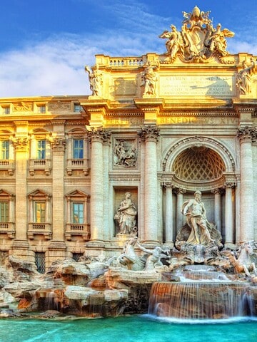 The Trevi Fountain in Rome, Italy, with ornate sculptures and turquoise water under a blue sky.