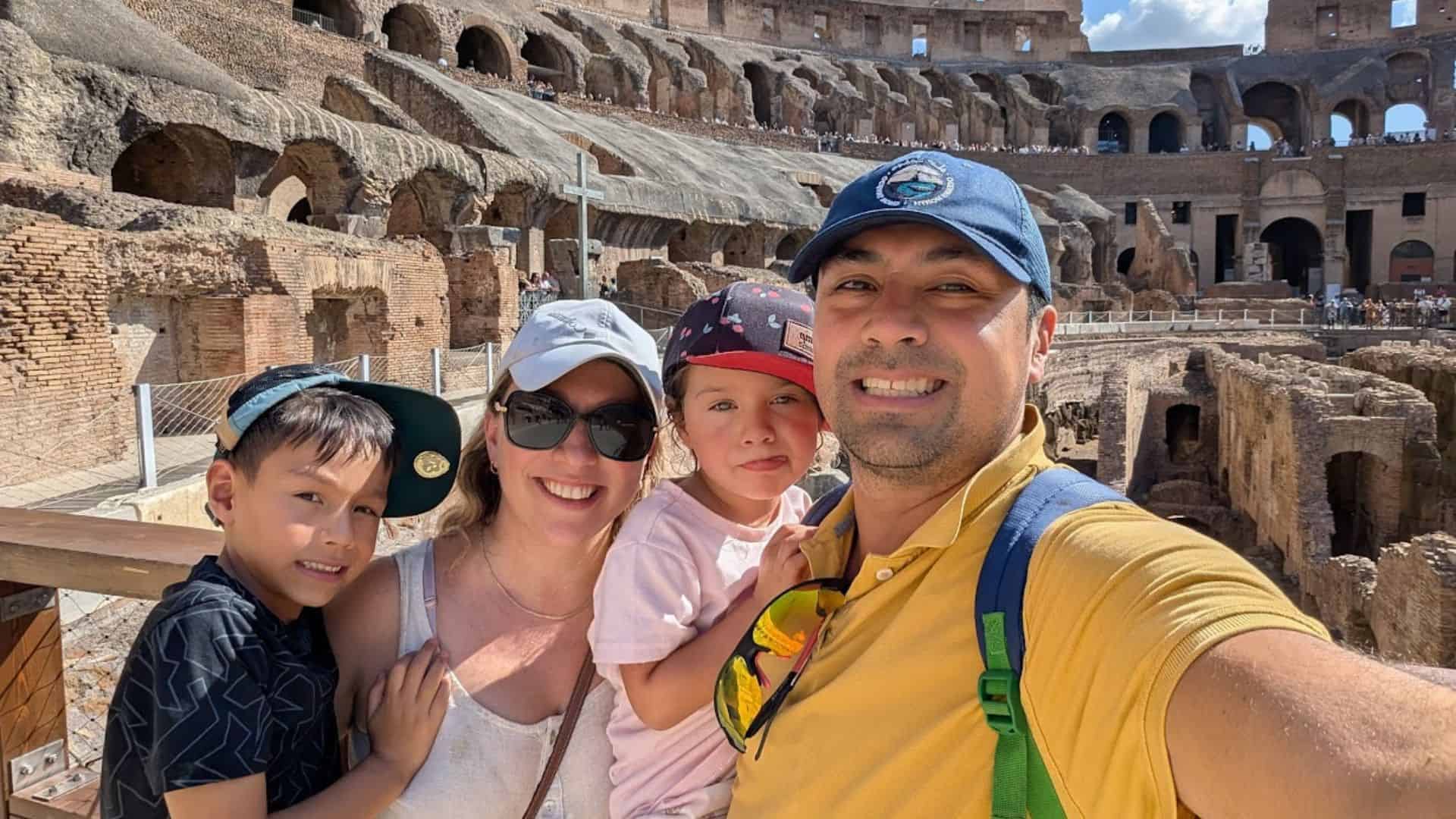 A family of four smiles for a selfie inside the Colosseum in Rome on a sunny day, creating memories for their perfect Rome with Kids family itinerary.