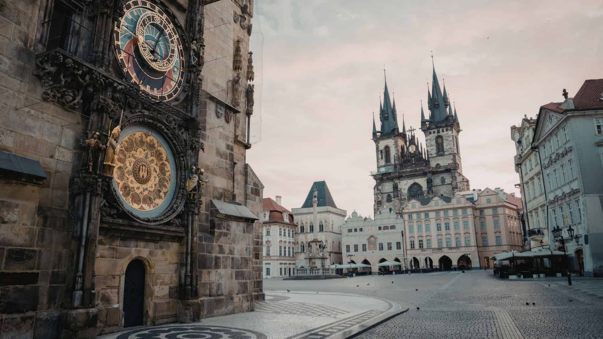 Prague&rsquo;s Astronomical Clock with T&yacute;n Church towers and empty Old Town Square at sunrise.
