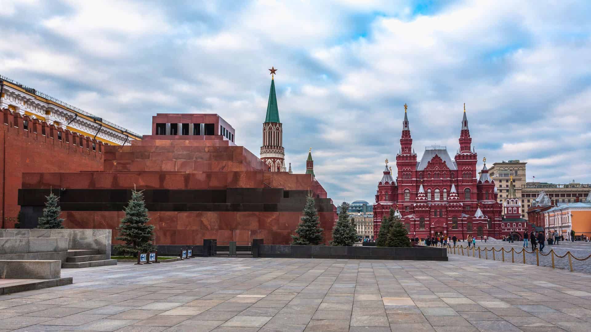 Red Square in Moscow with Lenin’s Mausoleum, Kremlin towers, and the State Historical Museum under a cloudy sky.