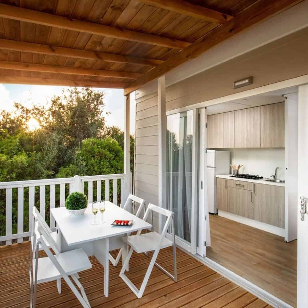 Sunny patio with a white table and chairs, next to an open sliding door leading into a modern kitchen&mdash;just moments from the scenic Parco della Gallinara.